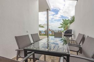 a dining room with a glass table and chairs at Villa Isabella, Luxury Villa with Heated Pool Ocean View in Adeje, Tenerife in Adeje