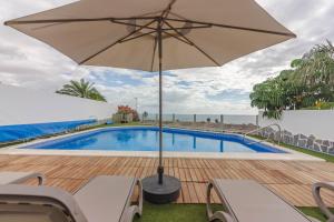 um pátio com um guarda-sol e uma piscina em Villa Isabella, Luxury Villa with Heated Pool Ocean View in Adeje, Tenerife em Adeje