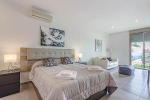 a white bedroom with a large bed and a couch at Villa Isabella, Luxury Villa with Heated Pool Ocean View in Adeje, Tenerife in Adeje