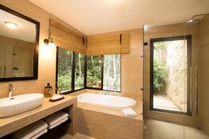 a bathroom with a tub, sink and mirror at Hotel Jungle Lodge Tikal in Tikal