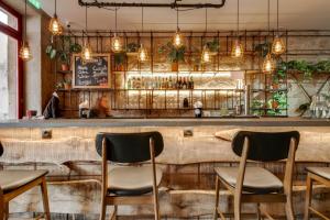 a restaurant with a bar with chairs and lights at Selina Porto in Porto