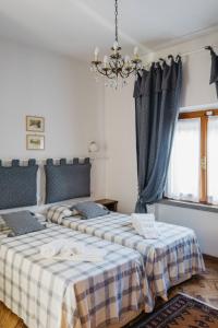 two beds in a bedroom with a chandelier at Casa Montecuccoli in Montelupo Fiorentino