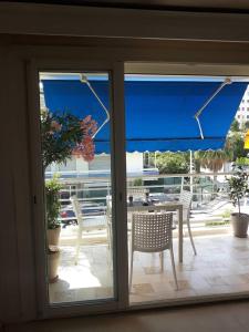 a patio door with a table and chairs and a blue umbrella at Palm beach Cannes Azur in Cannes