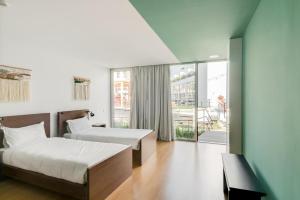 a hotel room with a bed, chair and a window at Selina Porto in Porto