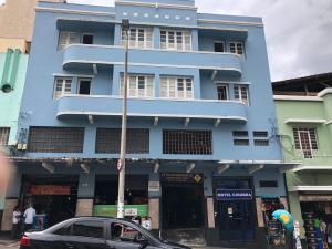 Un bâtiment bleu avec une voiture garée devant. dans l'établissement Motel Coimbra (Adults only), à Belo Horizonte