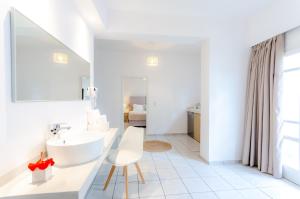 a white bathroom with a sink and a chair at Vergina Studios & Apartments in Malia