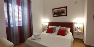 a bedroom with a white bed with red pillows at B&B Il Campanile in Sciacca