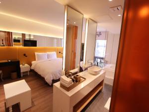 a bedroom with a bed and a bathroom with a mirror at Grammos Hotel in Seoul