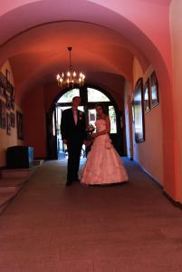 a bride and groom walking down a hallway at Hotel Panský dům in Nové Město na Moravě