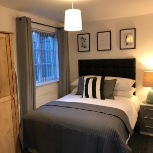 a bedroom with a bed with a black headboard and a window at Glaisdale Studios in Wolverhampton