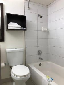 a bathroom with a white toilet and a tub and a sink at Inn Of Long Beach in Long Beach