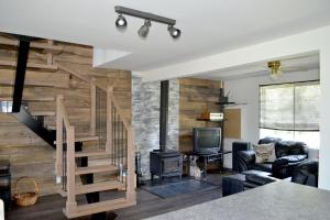 a living room with a wooden wall and stairs at Les 4 chalets - Le 609 in Lac-Saint-Paul