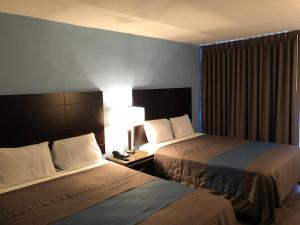 una camera d'albergo con due letti e una lampada di Inn Of Long Beach a Long Beach