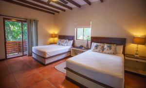 1 dormitorio con 2 camas y ventana en Boca Olas Resort Villas, en La Libertad