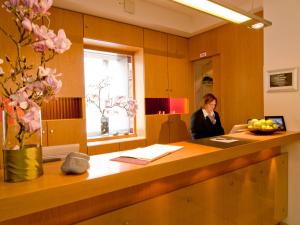 a woman standing at a reception desk in a office at ACHAT Hotel Regensburg Herzog am Dom in Regensburg