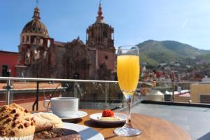 a glass of orange juice sitting on a table with food at Hotel Boutique Ponciano in Guanajuato