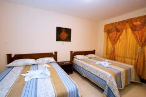 two beds in a hotel room with towels on them at Hotel El Cerro in Liberia