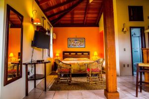 um quarto com uma cama, uma televisão e cadeiras em Hotel Pousada da Lagoa em Garopaba