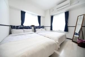 2 camas en una habitación blanca con ventanas en EX Itoman Apartment 203, en Itoman