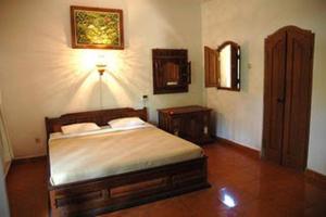 a bedroom with a bed and a lamp on the wall at Puri Bebengan Bungalows in Ubud