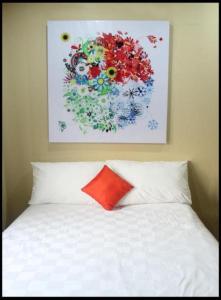 a bed with a red pillow and a painting on the wall at Maven Buncit in Jakarta