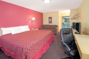 um quarto de hotel com uma cama vermelha e uma cadeira em Days Inn by Wyndham East Albuquerque em Albuquerque