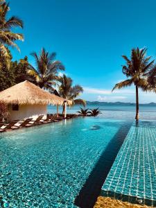 a swimming pool next to the ocean with palm trees at Sunrise Beach Resort in Ko Chang
