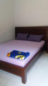 a bed with a wooden frame and purple sheets at Homestay dan Kost 78 in Jepara
