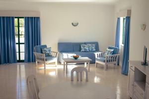 a living room with a blue couch and chairs at Dunas do Alvor - Torralvor in Alvor