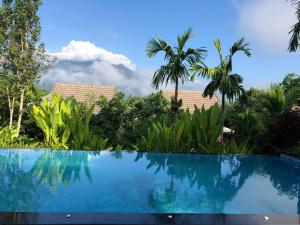 a blue swimming pool with palm trees in the background at Buraphat Resort in Chiang Dao