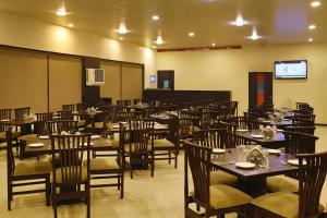 ein Esszimmer mit Tischen, Stühlen und einer Leinwand in der Unterkunft Hotel The Leaf in Aurangabad
