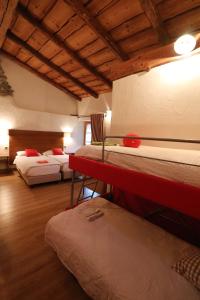 a room with three beds in a room with wooden ceilings at Ostello del Castello Tirano in Tirano