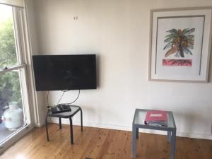 a living room with a flat screen tv and a table at Dutchies Beachside Retreat in Nelson Bay