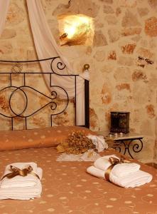 um quarto com toalhas numa cama com uma parede de pedra em Revera Traditional Stone Villas, Apartments & Studios em Kerion