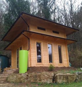 a small wooden house with a green container in front of it at Pension Am Waldrand in Mosbach