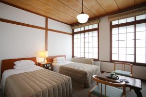 a room with two beds and a table and windows at Nikko Kanaya Hotel in Nikko