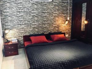 a bed with two red pillows and a brick wall at 08 Homestay in Can Tho