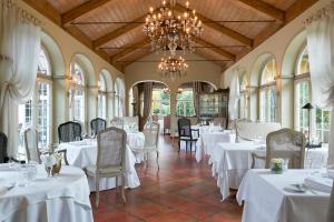 a restaurant with white tables and chairs and a chandelier at Hotel VILLINO in Lindau
