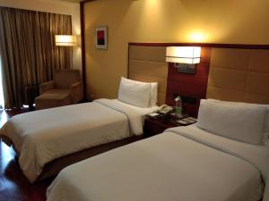 a hotel room with two beds and a chair at Park Inn Gurgaon in Gurgaon