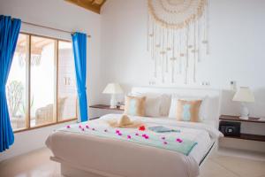 een slaapkamer met een groot wit bed met bloemen erop bij Sunrise Resort in Gili Air