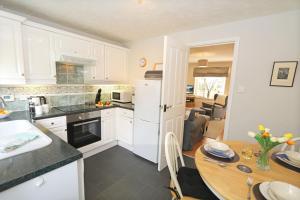 a kitchen with white cabinets and a wooden table at Hedgehope Cottage Alnwick in Alnwick +16 photos