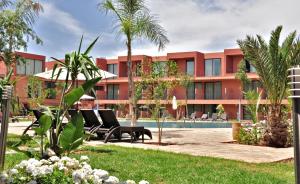 un complexe avec une piscine et des palmiers dans l'établissement Rawabi Hotel Marrakech & Spa, à Marrakech