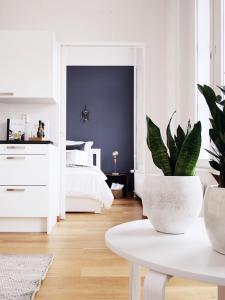 ヘルシンキにあるRoost Munkkisaariの白いベッドと鉢植えの植物が備わるベッドルーム1室