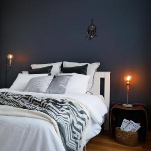 a bedroom with a large white bed with a blue wall at Roost Munkkisaari in Helsinki