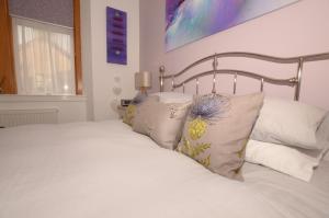 um quarto com uma cama com lençóis brancos e almofadas em The Stags Head Apartment em Inverness