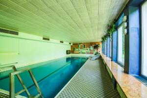an indoor swimming pool with blue water in a building at Kneipp-Kurhotel Emilie in Bad Wörishofen