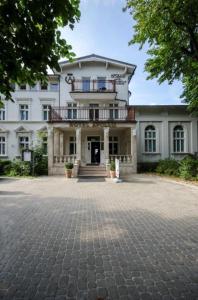 - un grand bâtiment blanc avec un balcon au-dessus dans l'établissement Domek Apartamentowy, à Darłówko