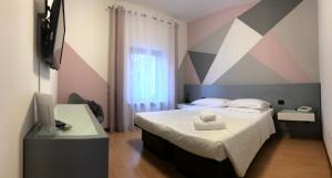 a bedroom with a bed with a striped wall at Hotel Gattopardo in Dossobuono