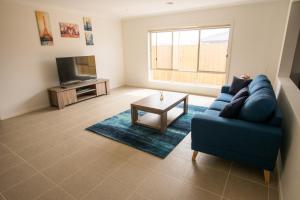 a living room with a blue couch and a tv at Apple House Point Cook in Point Cook