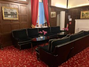 poczekalnia z czarnymi kanapami i stołami oraz czerwonym dywanem w obiekcie Hotel Pension Baron am Schottentor w Wiedniu